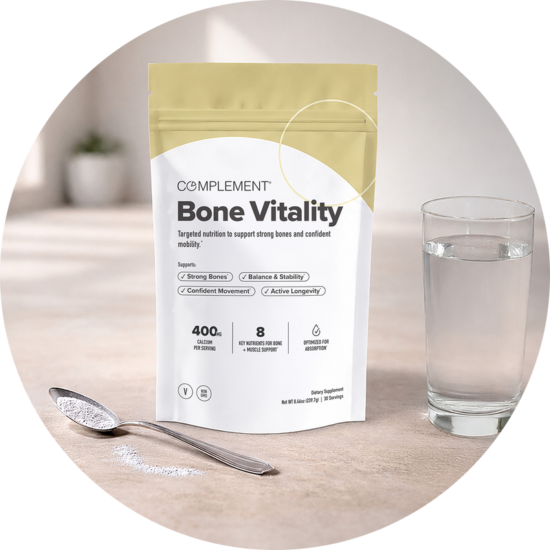 A pouch labeled Bone Vitality next to a full glass of water, a spoon, and some powder on a table. The pouch highlights bone and joint benefits and is positioned upright.