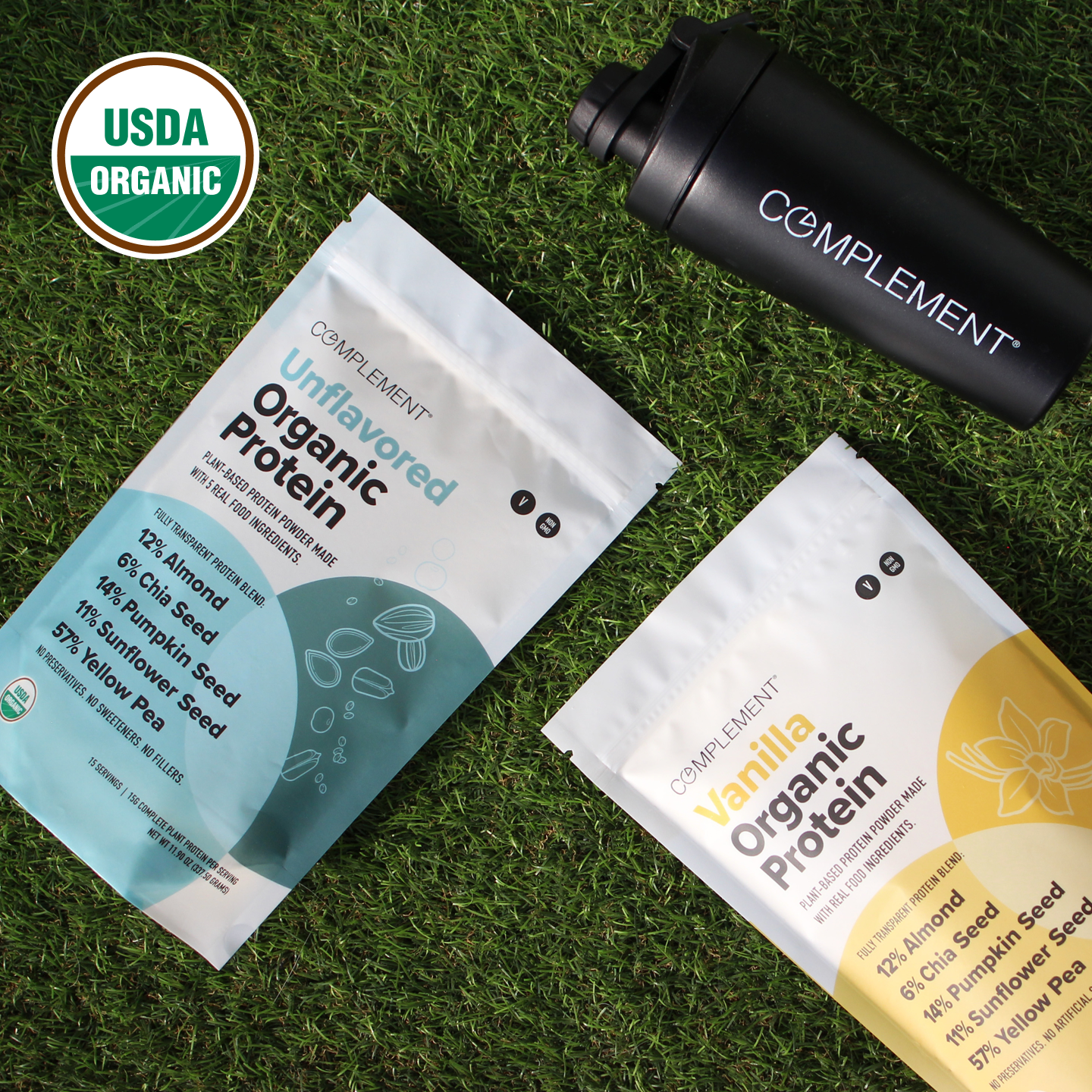 Two Complement organic protein powder bags, one unflavored and one vanilla, are on grass next to a black shaker bottle. A USDA Organic logo appears in the top left corner.