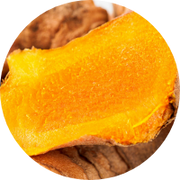 Close-up of a sliced turmeric root showing its vibrant orange interior and brownish outer skin.