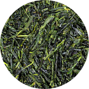 Close-up of loose green tea leaves, showcasing their rich, dark green color and slender, slightly twisted shapes. The leaves are packed closely together, filling the circular frame.