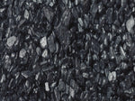 A close-up view of a pile of shiny, irregularly shaped black charcoal or coal pieces, showing their rough, jagged texture and reflective surfaces.