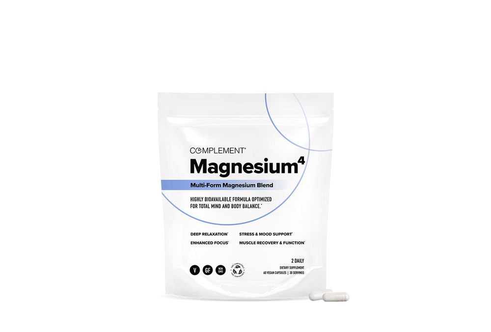A white bag labeled Complement Magnesium^4 Multi-Form Magnesium Blend stands upright, with two white capsules placed in front of it on a plain white background.