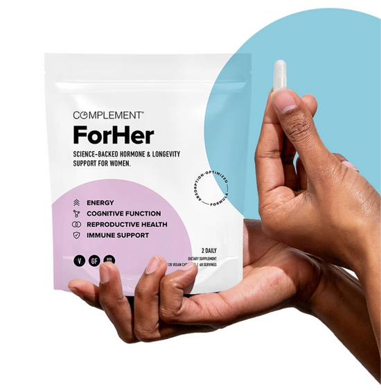 A person holds a small capsule next to a white pouch labeled Complement ForHer, which claims to support energy, cognitive function, reproductive health, and immune support. The background features blue and pink accents.