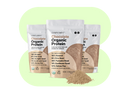 Three packages of Complements 3x Chocolate Protein powder sit against a light green background. The front package is open, with protein powder spilled in front. Labels highlight plant-based ingredients such as chia seed, almond, and yellow pea.