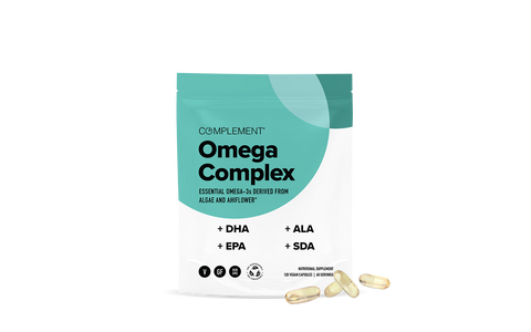 A teal and white pouch labeled Complement Omega Complex stands upright, with Omega-3 capsule supplements scattered in front. The packaging highlights DHA, EPA, ALA, and SDA as key ingredients.