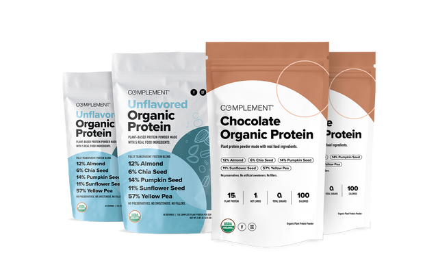 Four bags of Complement Organic Protein powder in Unflavored and Chocolate varieties. Packaging highlights ingredients like almond, chia, flax, pumpkin seed, sunflower seed, and yellow pea.