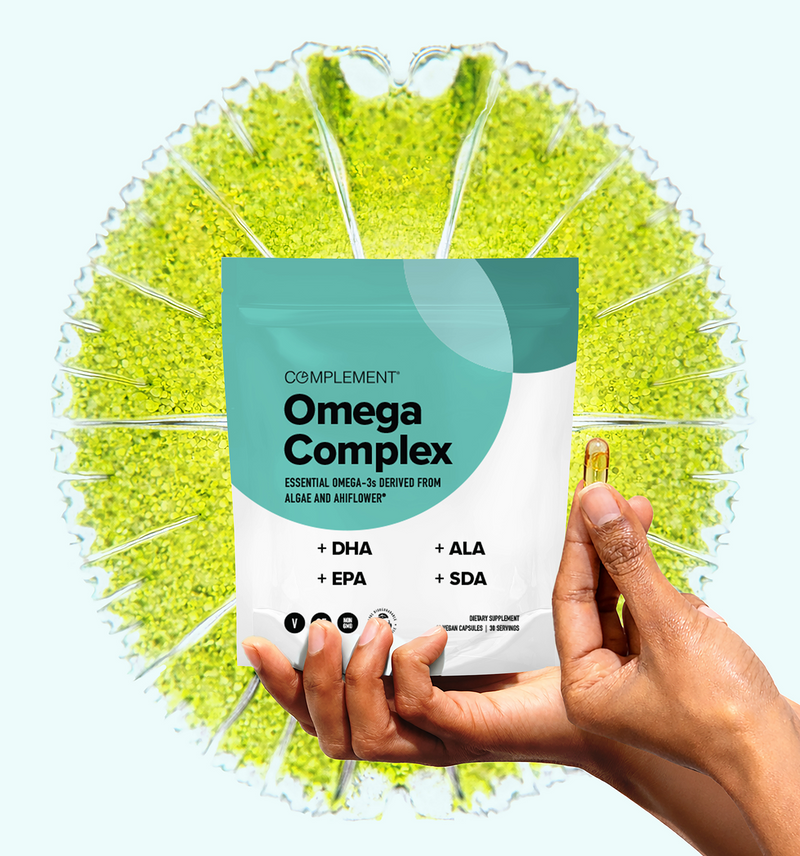 A hand holds a softgel capsule and a pouch labeled Complement Omega Complex with DHA, EPA, ALA, and SDA, set against a green algae background.
