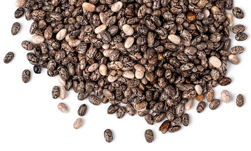 A pile of black and white chia seeds scattered on a white surface.