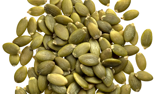 A pile of green pumpkin seeds is scattered on a white background.