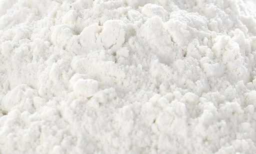 A close-up view of a pile of fine, white powder, likely flour, showing its soft, crumbly texture.
