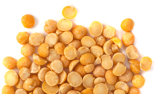 A pile of dried yellow split peas scattered on a white background.