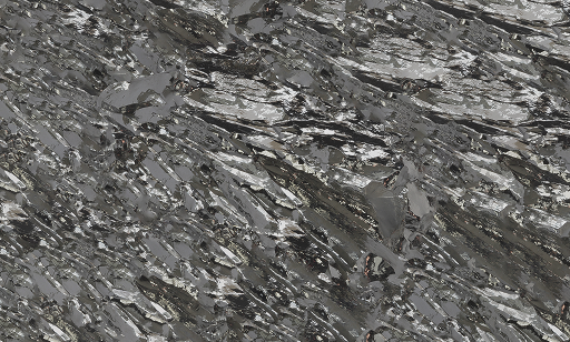 Close-up view of shiny, silver-gray metallic crystals with jagged, layered, and angular surfaces reflecting light, creating a textured, reflective pattern across the image.