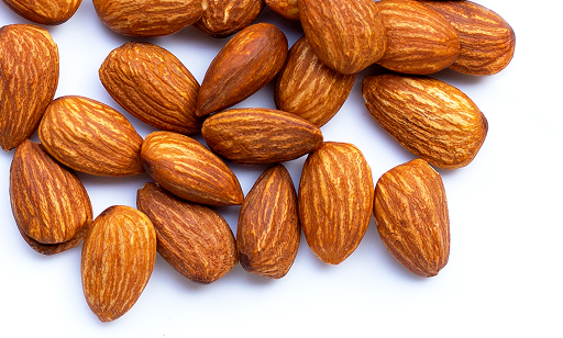 A close-up of several whole, unshelled almonds scattered on a white surface.
