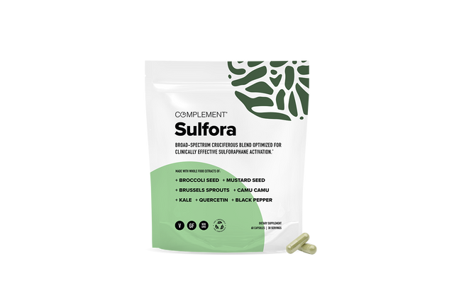 A white and green pouch labeled Complement Sulfora with broad-spectrum cruciferous blend ingredients listed, including broccoli seed, mustard seed, brussels sprouts, camu camu, kale, quercetin, and black pepper. Two capsules are beside the pouch.