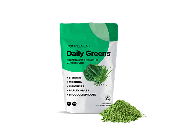 A green and white package labeled Daily Green 5 by Complement, featuring spinach, moringa, chlorella, barley grass, and broccoli sprouts. A small pile of green powder is next to the package.