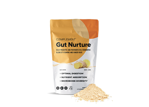 A package of Complement Gut Nurture is shown, featuring a daily prebiotic and postbiotic blend with vitamins and ginger root. The packaging highlights benefits like optimal digestion, nutrient absorption, and microbiome diversity. Powder is spilled in front.