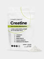 A white pouch labeled COMPLEMENT® Creatine by Complement stands upright with white powder spilled beside it. The package highlights benefits such as brain health, energy, muscle recovery, longevity, and reproductive health.