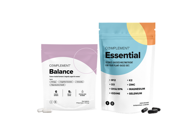 Two supplement pouches labeled Balance and Essential with capsules and softgels in front. The Balance bag is pink and white, while Essential is blue, orange, and white, listing nutrients on the front.