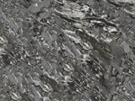 Shiny, metallic, silver-gray mineral crystals with jagged, layered, and reflective surfaces tightly packed together, creating a textured, abstract pattern.