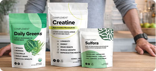 Three supplement packages labeled Daily Greens, Creatine, and Sulfora are displayed on a counter. A person stands behind them with arms resting on the surface, but their face is not visible.