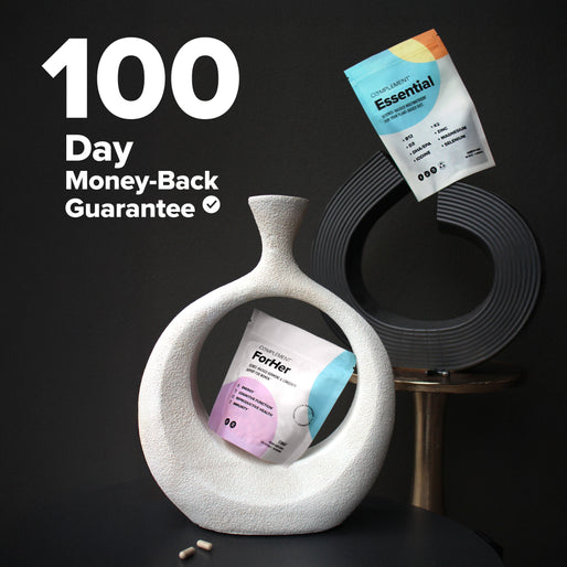 Two supplement bags displayed as art, one inside a white circular vase and the other clipped above a black circular sculpture. Text reads 100 Day Money-Back Guarantee on a black background. Two capsules rest in front.