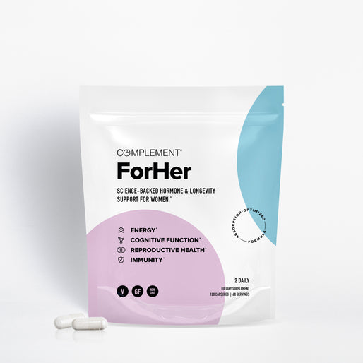 A white pouch labeled Complement ForHer dietary supplement stands upright, featuring icons and text highlighting benefits for energy, cognitive function, reproductive health, and immunity. Two white capsules lie in front.