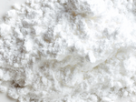 A close-up of a mound of fine white powder with a soft, fluffy texture on a white surface.