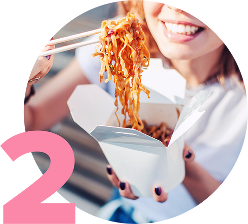 A person is smiling while eating noodles with chopsticks from a white takeout box. The image has a pink number 2 on the left. The scene suggests a casual, enjoyable dining experience outdoors.