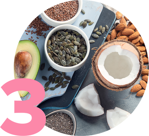 A variety of healthy foods are displayed on a circular surface: sliced avocado, bowls of flaxseeds, pumpkin seeds, a halved coconut, almonds, and chia seeds. A large pink number 3 is in the bottom left corner.