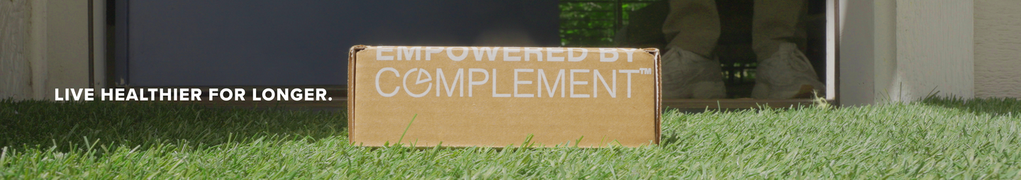 A brown box labeled EMPOWERED BY COMPLEMENT sits on green grass in front of a door, with the text LIVE HEALTHIER FOR LONGER. displayed to the left.