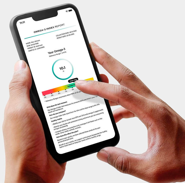 A person holding a smartphone displaying an Omega-3 index report. The report shows a score of 10.1% on a colored scale. The screen also contains some text details below the scale.