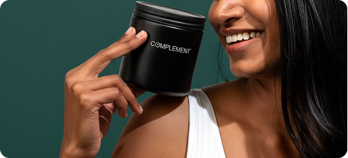 A smiling woman in a white top holds a black container labeled COMPLEMENT near her face against a dark green background.