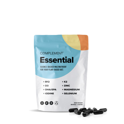 A white package labeled Complement Essential with a colorful design contains multinutrient supplements. The packaging lists B12, D3, DHA/EPA, Iodine, K2, Zinc, Magnesium, and Selenium. Five black capsules are displayed in front.