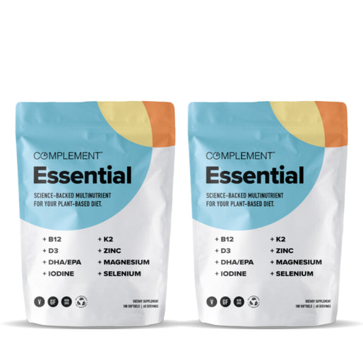 Two bags of Complement Essential multivitamins for plant-based diets, featuring nutrients like B12, D3, DHA/EPA, iodine, K2, zinc, magnesium, and selenium. The packaging is predominantly white with blue and orange accents.