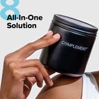 Woman holding matte black glass jar that stores Complement Essential vegan multivitamin with text that reads All-In-One Solution.