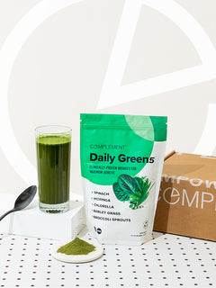 Photo of Complement Daily Greens powder in glass of water