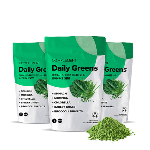 Three green and white bags of Daily Green powder featuring spinach, moringa, chlorella, barley grass, and broccoli sprouts. A small pile of green powder is in front of the bags.